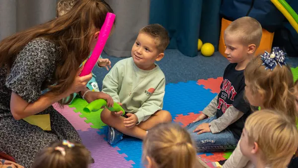Young children sit on a colorful play mat at a UNICEF-supported Spilno Child Spot in Kharkiv, Ukraine.