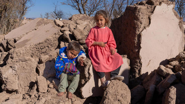 On Dec. 3, 2023, children sit for a portrait on a pile of rubble where their home used to stand in earthquake-affected Zinda Jan district, Herat province, Afghanistan. 