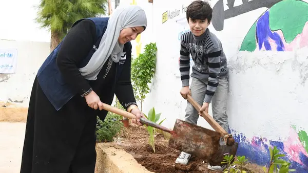 A mother and her son in Jordan plant vegetation at a Climate Action Club.