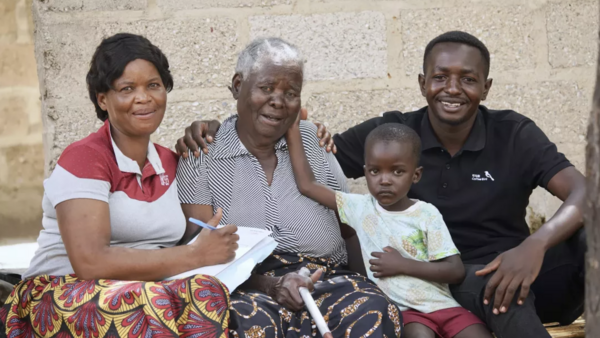 A UNICEF-supported volunteer (far left) visits a family affected by cholera in Zambia.