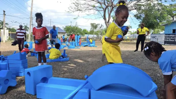 Children from National Water Commission Credit Union Basic School playing with blue blocks at the pop-up playground supported by UNICEF.