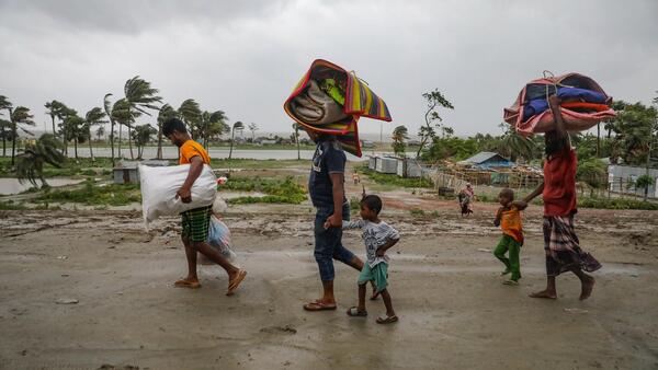 Parents and children head to a shelter ahead of Cyclone Remal's landfall in Bangladesh on May 26.