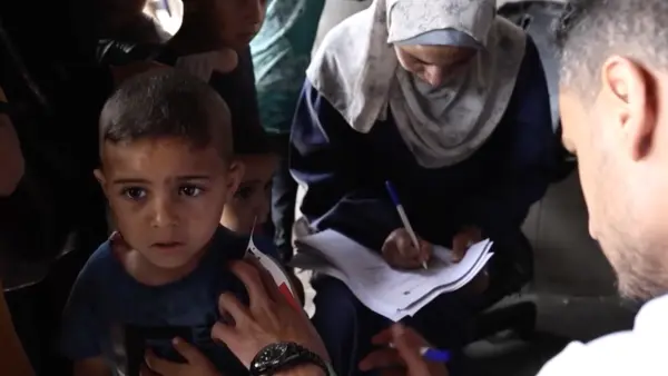 A health worker from a UNICEF-supported pediatric clinic screens children for malnutrition and delivers high-energy biscuits in northern Gaza Strip on May 27, 2024. 