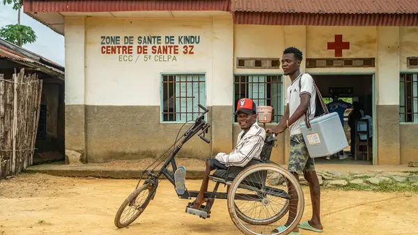 From left: Rajabu Vambise, 27, polio survivor and UNICEF-supported community worker, with a vaccinator during a polio vaccination campaign in Kindu, Maniema province, Democratic Republic of the Congo, on March 30, 2024.