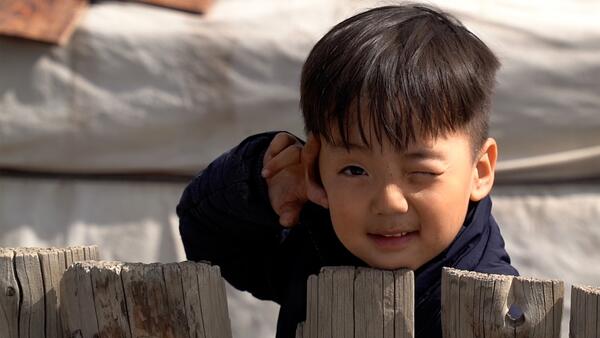 J. Khuvituguldur, 4, peeks over the fence behind his family's ger home in the outskirts of Ulaanbaatar, Mongolia.