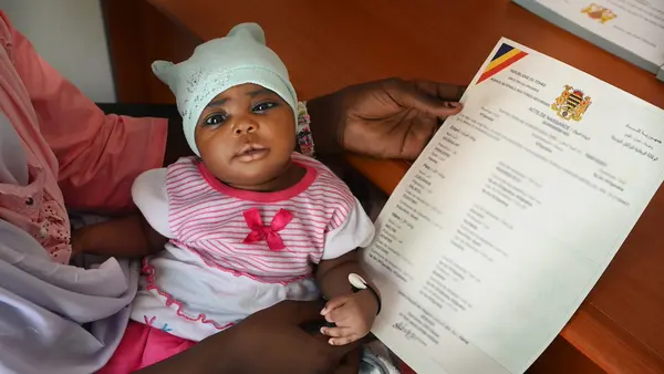 Fatima Mahamat, 20, holds her 23-day-old baby girl Amina in her lap and the child's new birth certificate in her hand, having completed the registration in just a few minutes using a digital app, at the health center in N’Djamena, the capital of Chad, where the child was vaccinated.