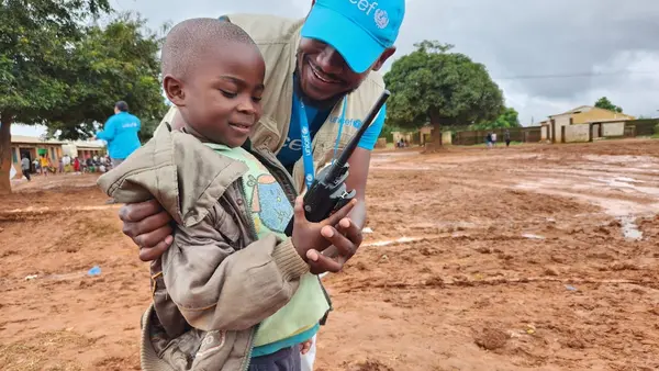 A UNICEF staff member shares a light moment with a young Cyclone Freddy survivor at the UNICEF-supported Naotcha camp for displaced families in Blantyre, Malawi, on March 17, 2023.