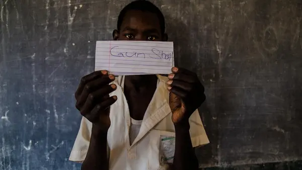 A student at a school in northeast Nigeria holds a paper showing his greatest fear, part of an exercise to identify strengths and vulnerabilities at school and in the community.
