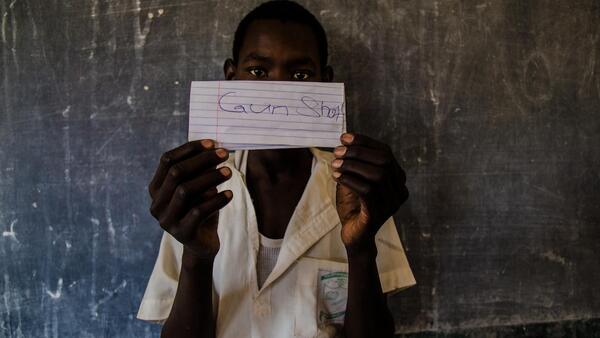 A student at a school in northeast Nigeria holds a paper showing his greatest fear, part of an exercise to identify strengths and vulnerabilities at school and in the community.