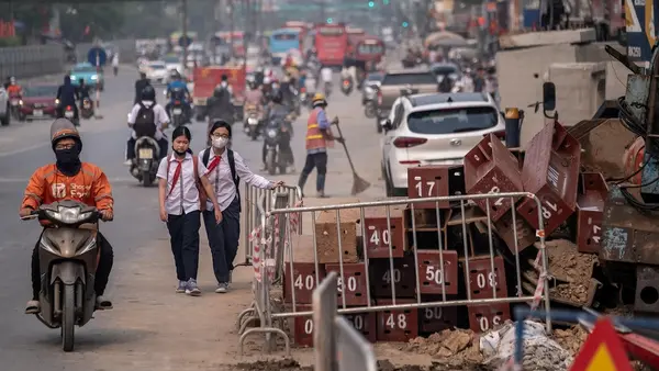People wearing masks navigate through a dusty construction area on Kim Dong Street, Hai Ba Trung District, Hanoi, Vietnam.