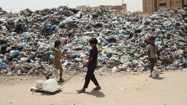 Children pass through a waste dump while searching for clean,safe drinking water in Rafah, southern Gaza Strip.