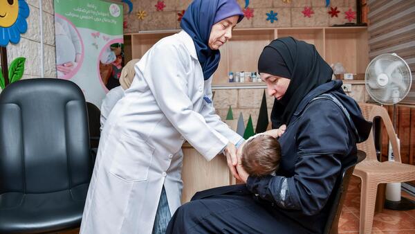 A pediatrician shows a mother a breastfeeding position at a UNICEF-supported health and nutrition center in Harasta, Rural Damascus, Syria. 