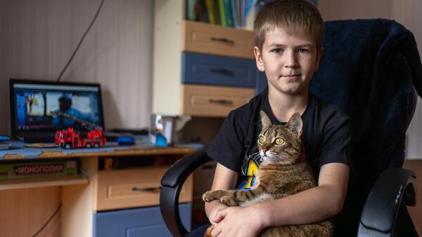 Nine-year-old Andrii holds his cat in his bedroom in Kherson, Ukraine. 