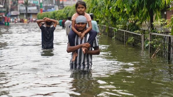 A father carries his child on his shoulders as he wades through floodwaters in Feni, southeastern Bangladesh.