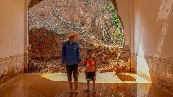 A mother and son stand inside their flooded home in Lao Cai province, Vietnam after Super Typhoon Yagi.
