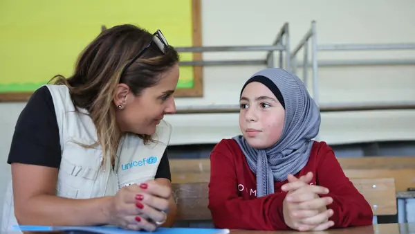 On Sept. 24, 2024, a UNICEF staff member speaks with Mariam, 10, displaced by violence and staying with her family in Amiliye public school, now being used as an IDP shelter, in Beirut, Lebanon. 