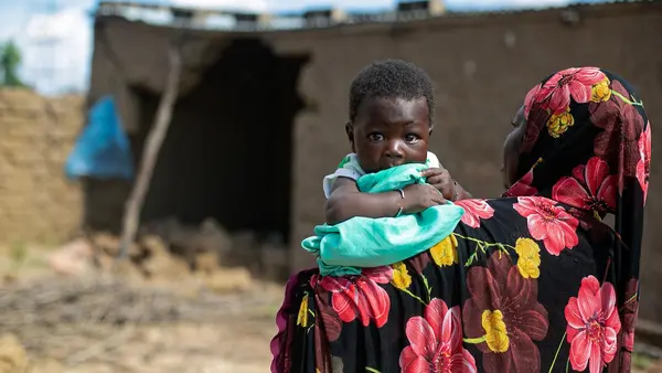 A mother holds her 2-month-old infant outside the flood-damaged family home in Sirebougou village, Ségou region, Mali.