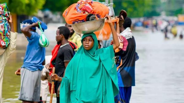Residents of flooded communities in Maiduguri, Nigeria, wade through floodwaters. 
