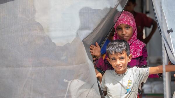 In Al-Khawkhah district, Al-Hudaydah governorate, Yemen, a brother and sister step outside a tented classroom where children affected by conflict are able to resume their education with UNICEF support.