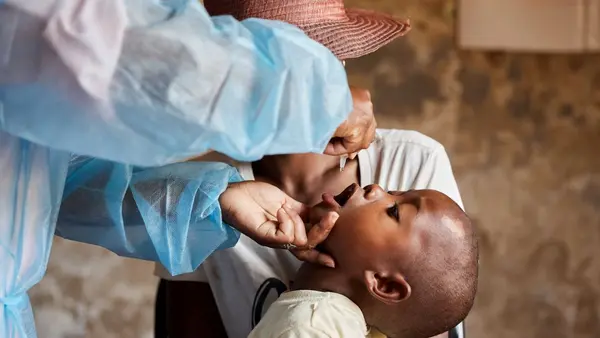 A health care worker administers the polio vaccine to a young child.