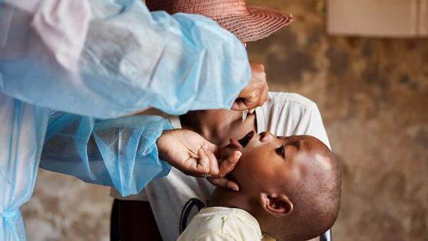 A health care worker administers the polio vaccine to a young child.