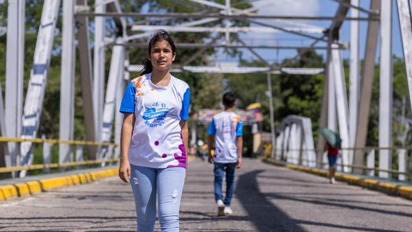 Wearing a UNICEF shirt, Aime, a 14-year-old migrant from Venezuela, crosses a bridge in Colombia. 
