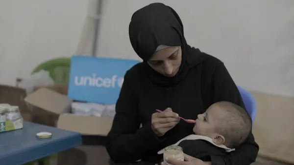 A mother feeds her baby supplementary food at a UNICEF nutrition point in Gaza City. 