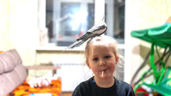 In Balakliia, Ukraine, 3-year-old Katya smiles as a pet bird rests on her head.
