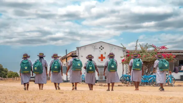 Female Village Health Workers with backpacks and backs turned to camera in Zimbabwe