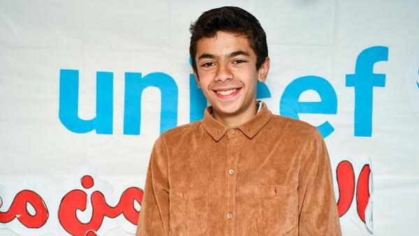 Mohammed, 15, stands in a UNICEF-supported child-friendly space, with a banner partially displaying the UNICEF name behind him, in Bseimeh village, Rural Damascus, on Feb. 2, 2025.