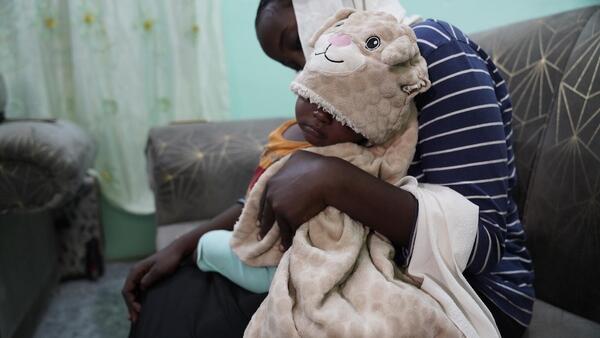 Raped by armed men in Khartoum at the age of 17, a young woman holds her baby son on her lap.
