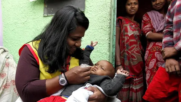 Minda Dentler, a Rotary ambassador, administers the polio vaccine to a child during a national immunization campaign in India.