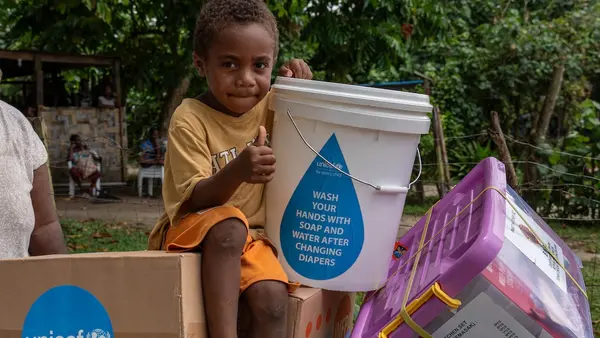 Four-year-old Johnathan sits holding items included in an emergency kit distributed by UNICEF and partners to earthquake-affected families in Erakor Bridge Community in south Efate, Vanuatu, in December 2024.