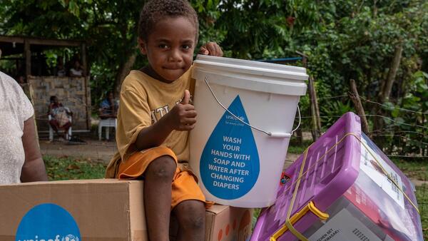 Four-year-old Johnathan sits holding items included in an emergency kit distributed by UNICEF and partners to earthquake-affected families in Erakor Bridge Community in south Efate, Vanuatu, in December 2024.