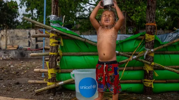 On April 6, 2025, a boy bathes beside a temporary water tank made with tarpaulin provided by UNICEF at a makeshift tent camp in Amarapura township, Mandalay region, Myanmar, following the recent earthquake. 
