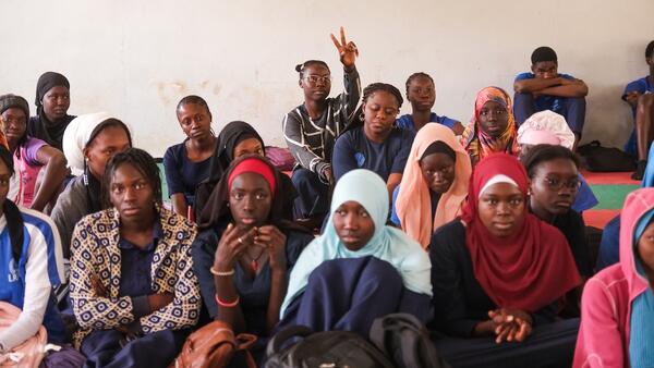 A student raises her hand in the back of a Senegal classroom while participating in a Women’s Teachers Network workshop about menstrual hygiene.