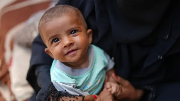 Baby boy smiling at the camera while being held