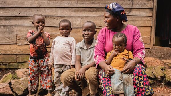 In South Kivu province, DRC, a mother sits with her four children outside her drink stall, a business she started with cash assistance from UNICEF that is helping the family survive.