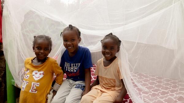 In Blue Nile state, Sudan, girls sit under a bed net provided by UNICEF to prevent malaria, a mosquito-borne illness.