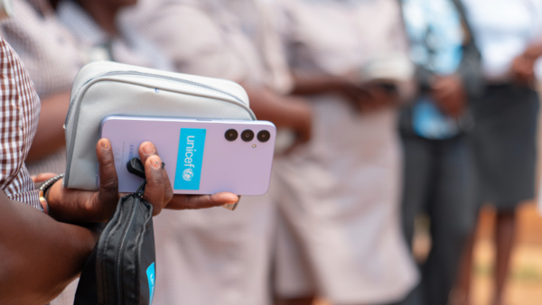 Woman's hand holds smartphone with UNICEF logo on the back of the device