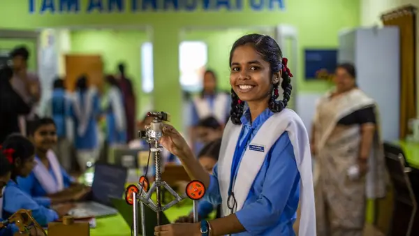 Smiling girl in blue shirt standing in front of table 