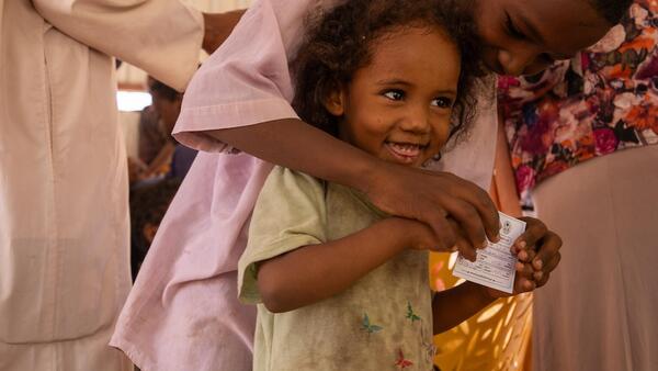 In Khartoum State, Sudan, two children hold a certificate showing they have received their oral cholera vaccine, delivered by UNICEF.