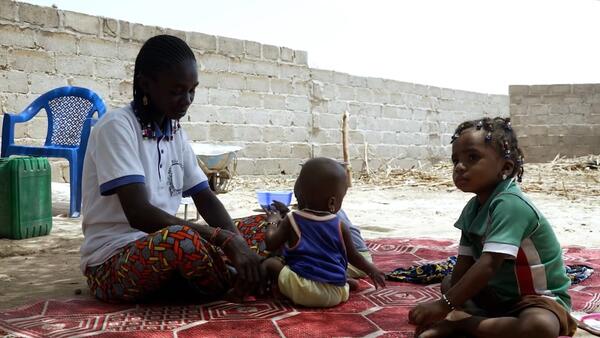 Displaced by violence, a mother and her children sit outside in Burkina Faso. 