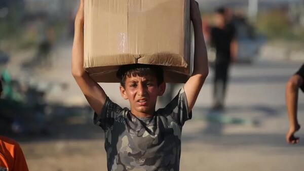 A 13-year-old boy balances a box of humanitarian aid on his head in the Gaza Strip.