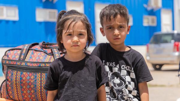 Amir Ali, 5, and Baran, 3, sit next to their family’s belongings in the reception area at the Islam-Qala border crossing, just hours after returning to Afghanistan. 