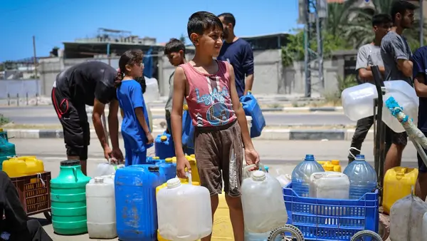 A Palestinian boy holds water containers at a water distribution point in the Gaza Strip.