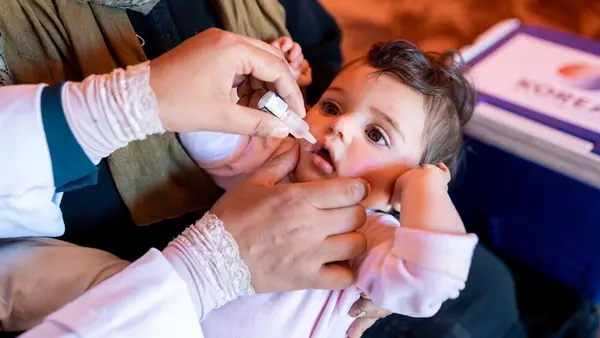 A 9-month-old receives an OPV vaccine from a UNICEF-supported health worker in an informal tented settlement in Ajloun, Jordan. 