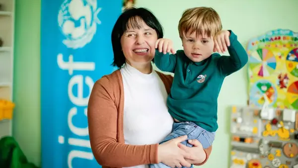 A UNICEF-trained librarian holds a young child in her arms in Bortnyky, Lvivska region, Ukraine.