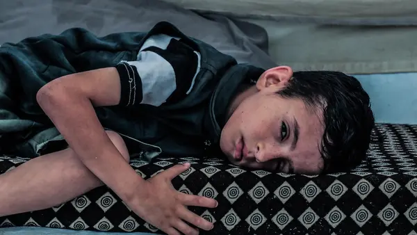 A 7-year-old boy badly injured by shrapnel lies on a mat in the Gaza Strip on June 14, 2025.