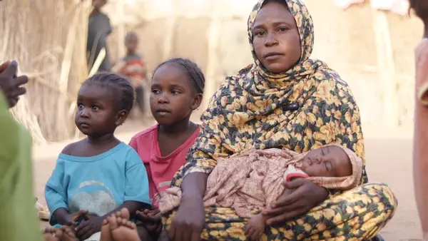 A mother and her three children sit outside the shelter where they live in Tawila, Sudan after fleeing conflict in Al Fasher. 